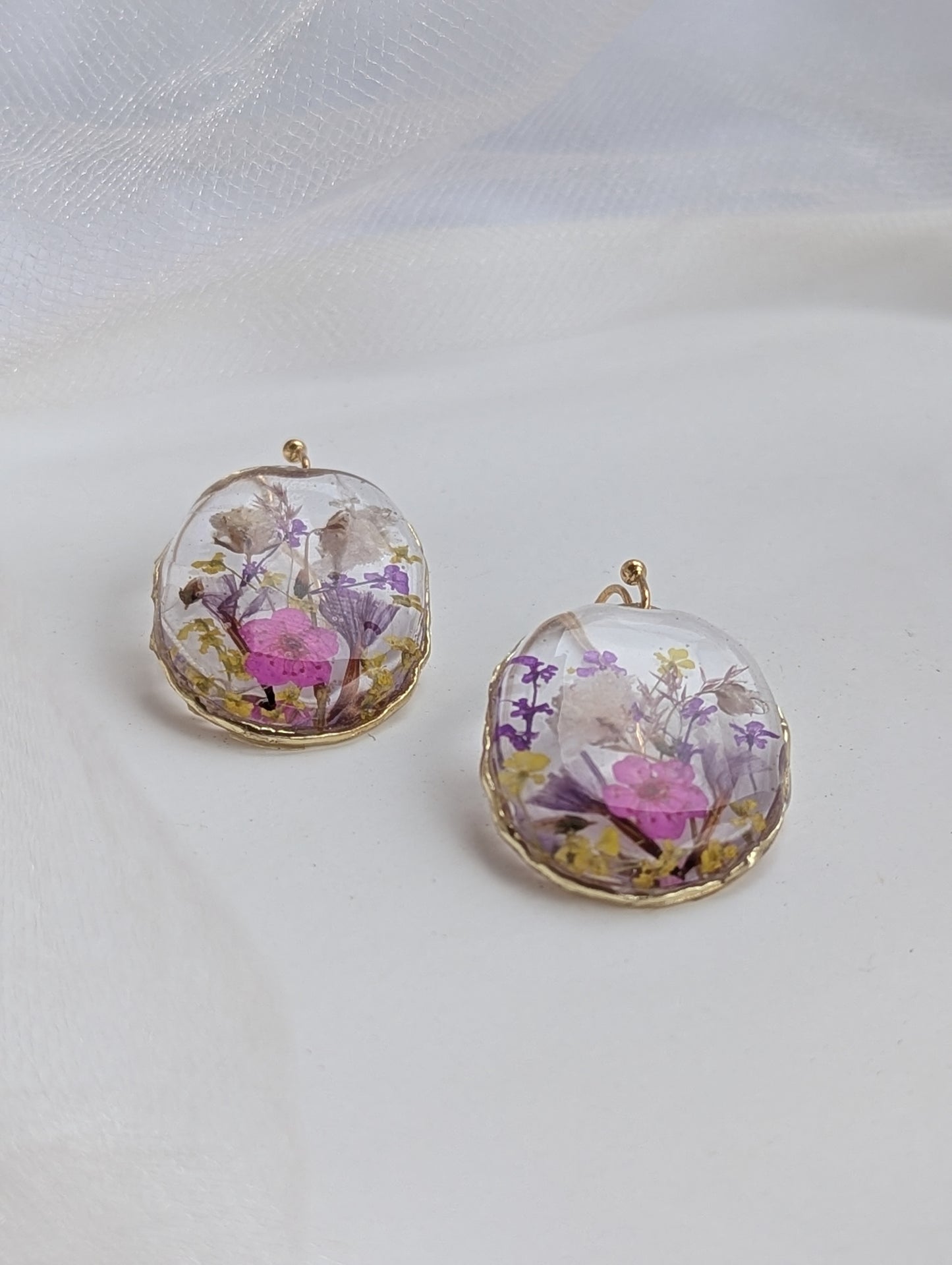 Pair of earrings with floral design in clear dome on a light background