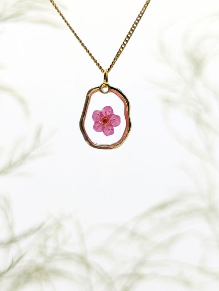 Necklace with a pink flower pendant on a white marble background