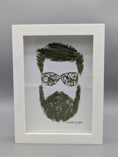 Framed artwork of a face made from leaves on a gray background