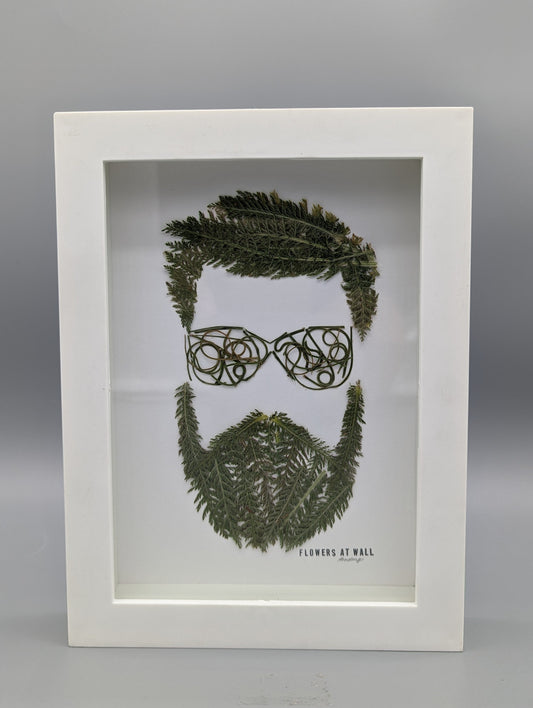 Framed artwork of a face made from leaves on a gray background