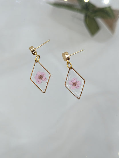 Gold geometric earrings with pink floral design on a light background