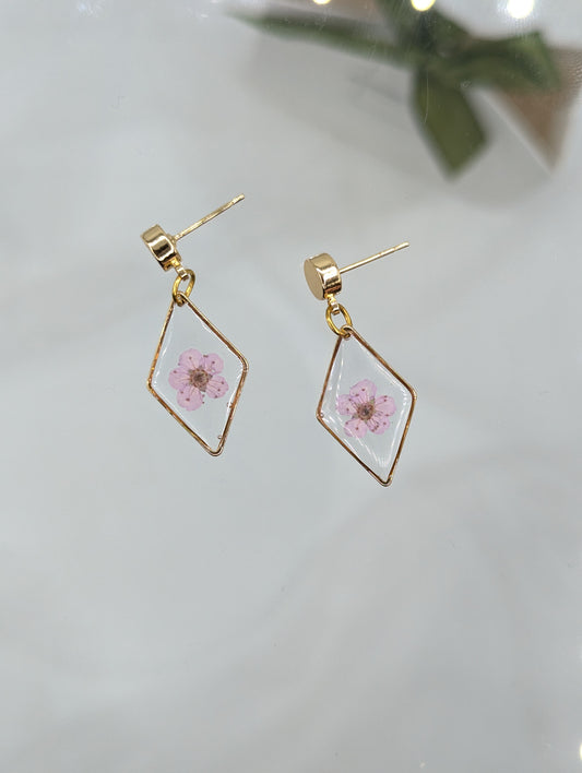Gold geometric earrings with pink floral design on a light background