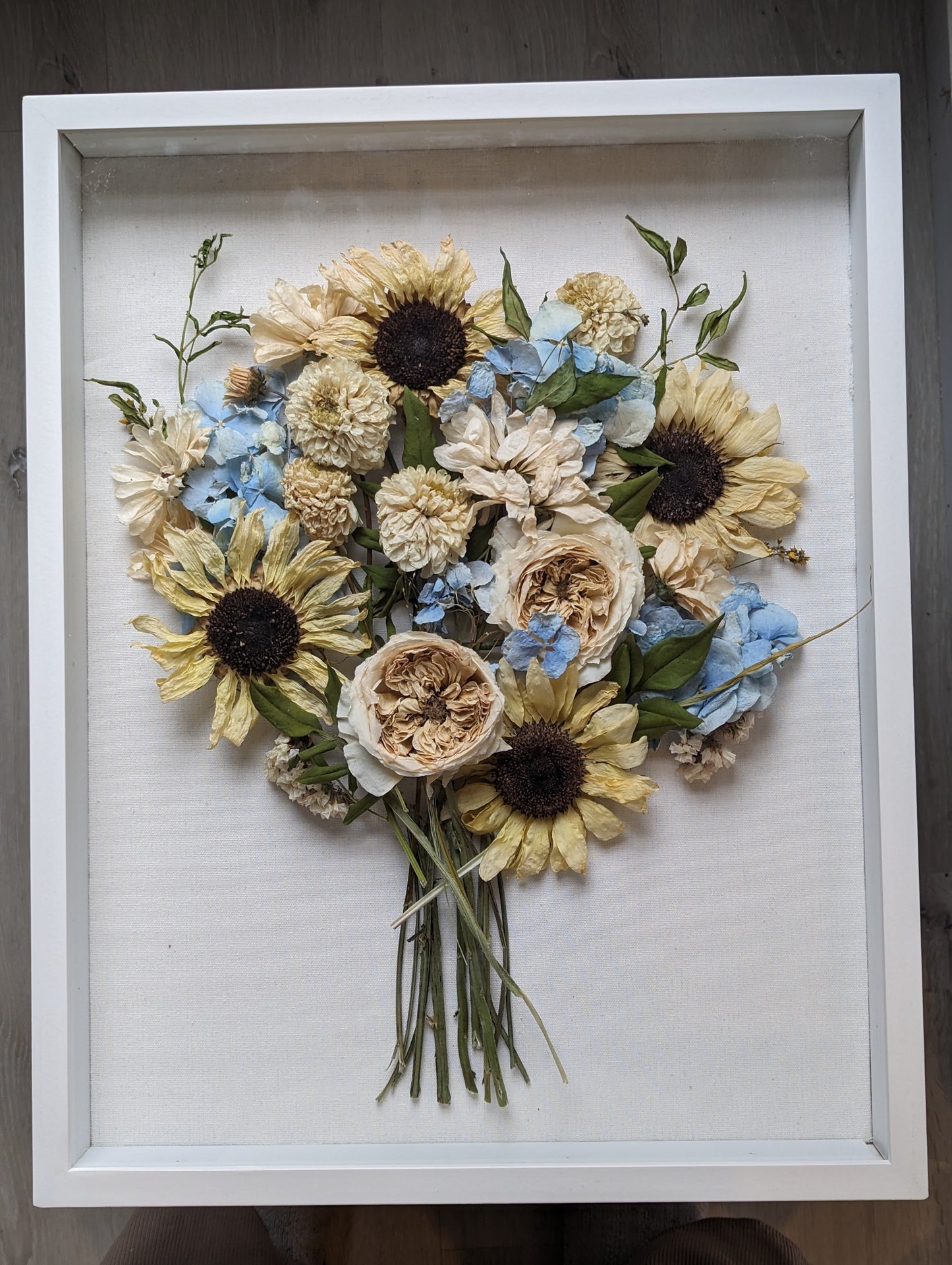 Framed arrangement of pressed flowers on a wooden surface