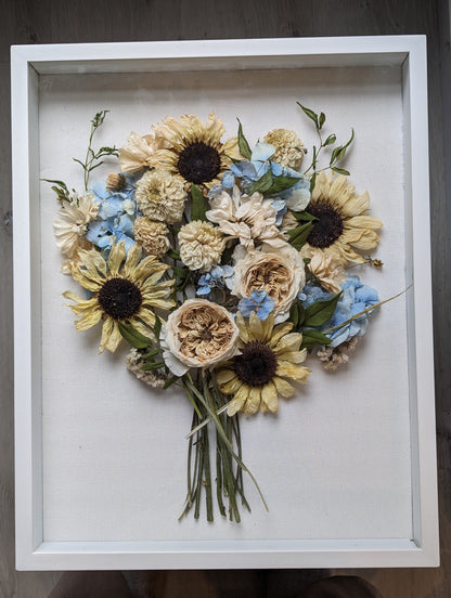 Framed arrangement of pressed flowers on a wooden surface