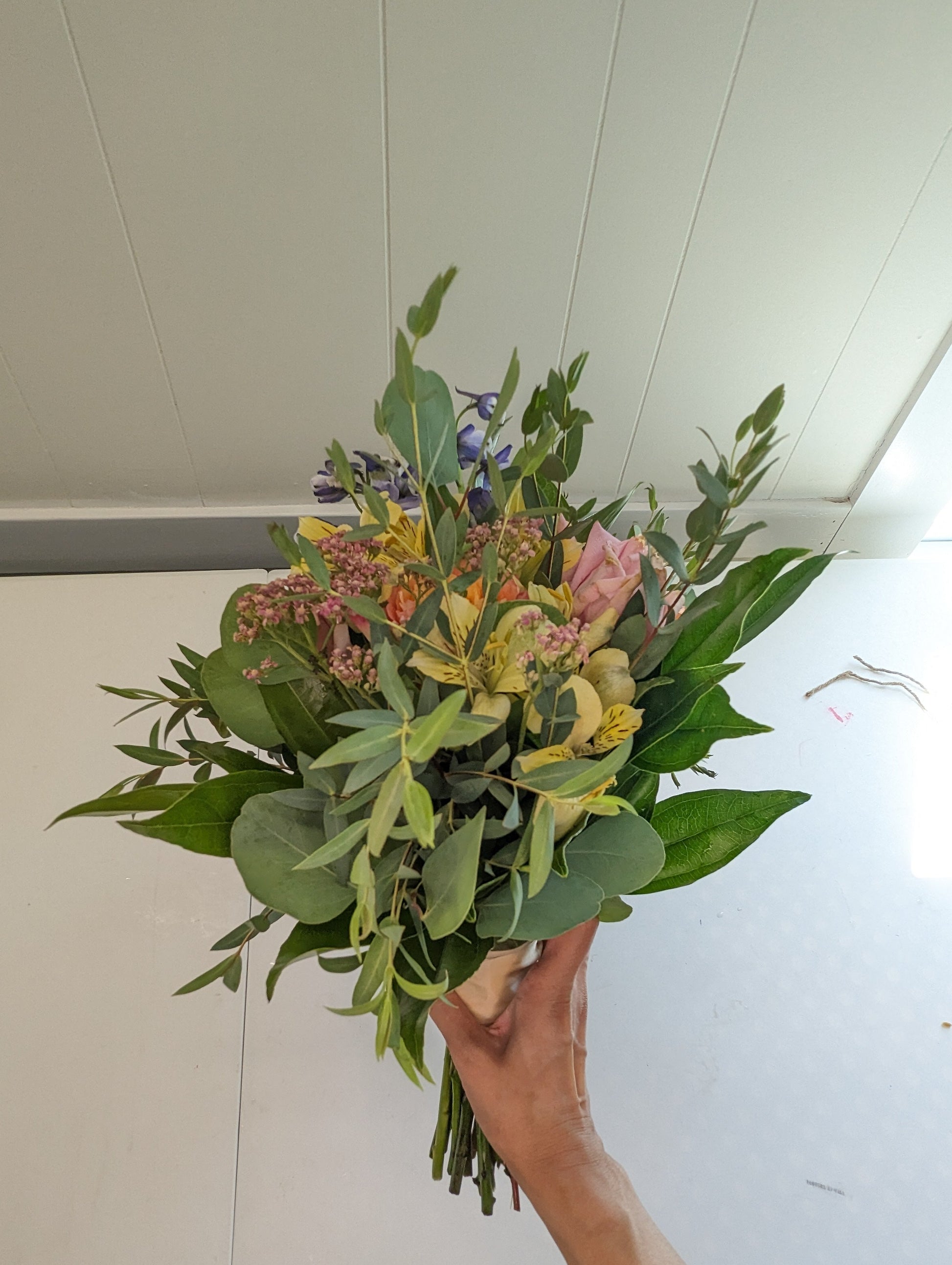 Bouquet of flowers held in front of a white wall