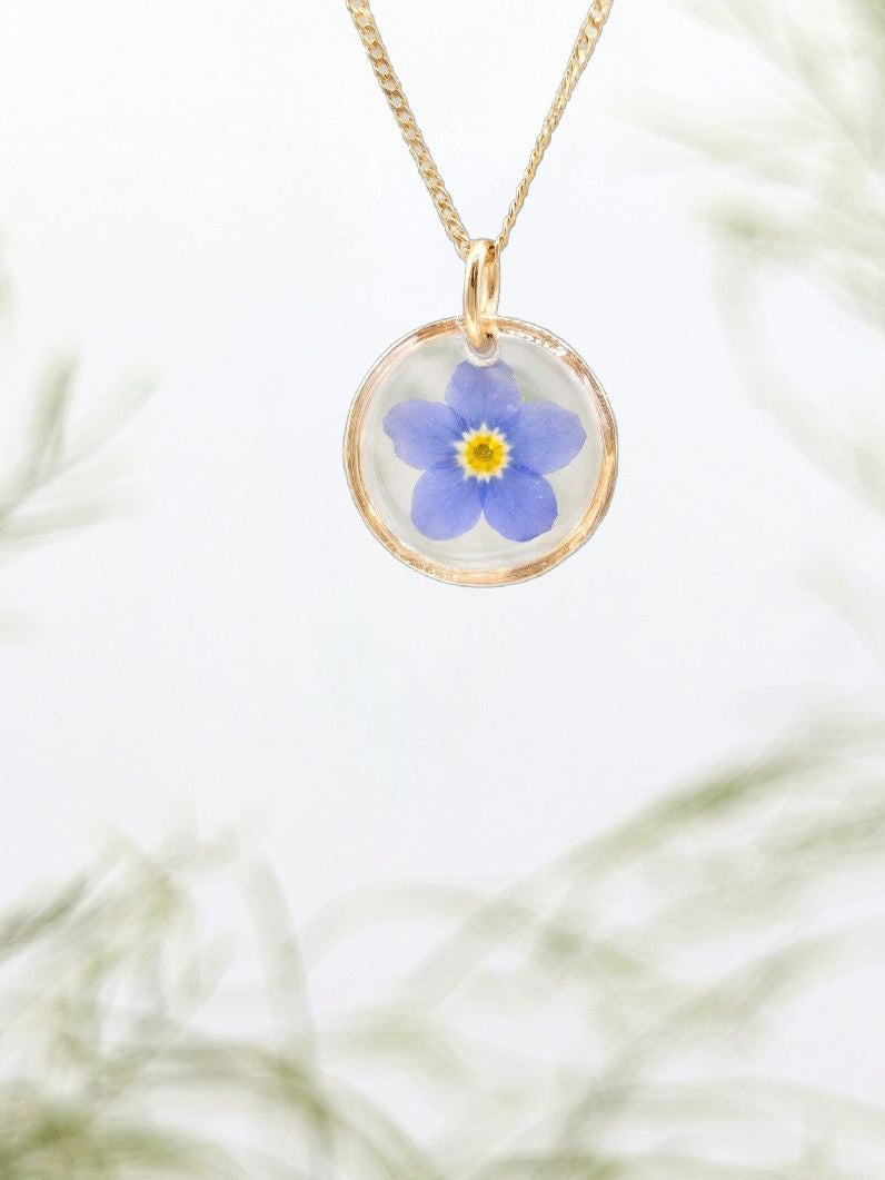 Necklace with a pendant featuring a blue flower on a white background