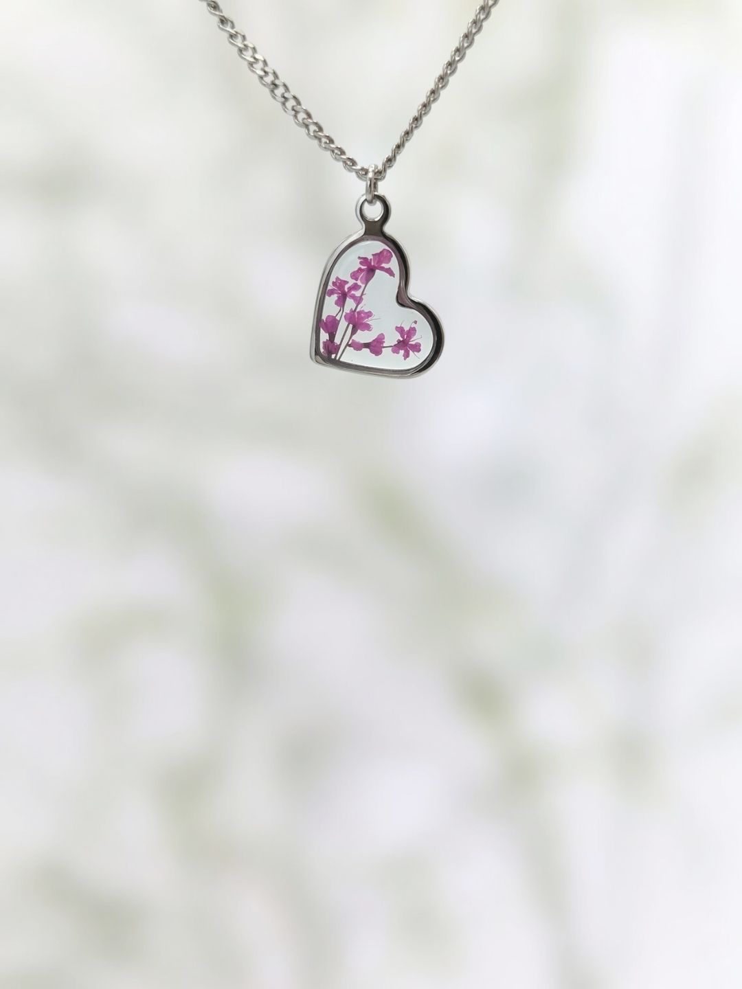 Heart-shaped pendant with floral design on a blurred natural background