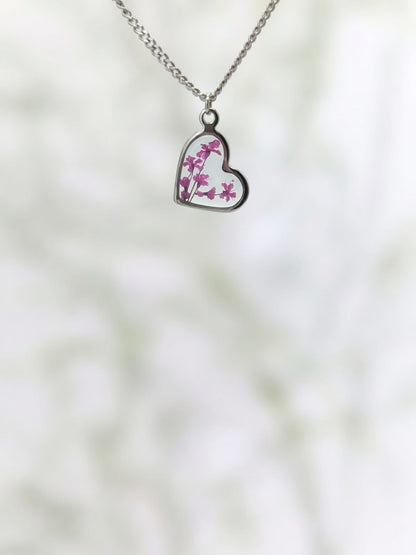 Heart-shaped pendant with floral design on a blurred natural background