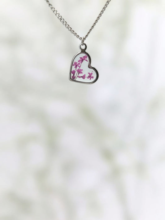 Heart-shaped pendant with floral design on a blurred natural background