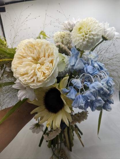Bouquet of flowers including white, yellow, and blue elements on a white background