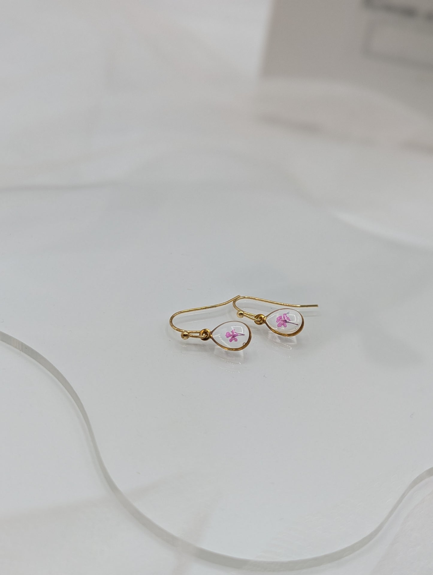 Gold hoop earrings with pink gemstones on a white surface