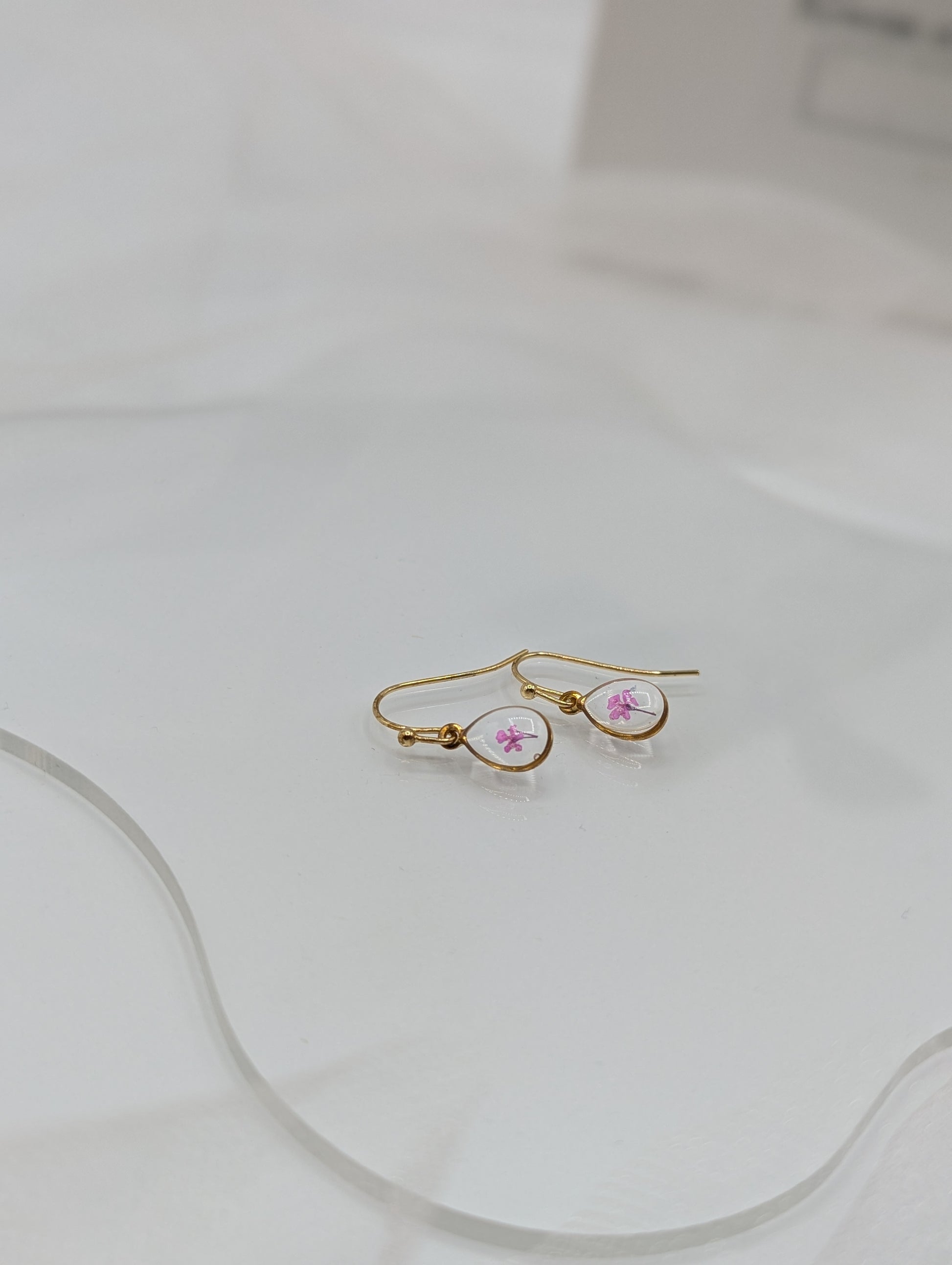 Gold hoop earrings with pink gemstones on a white surface