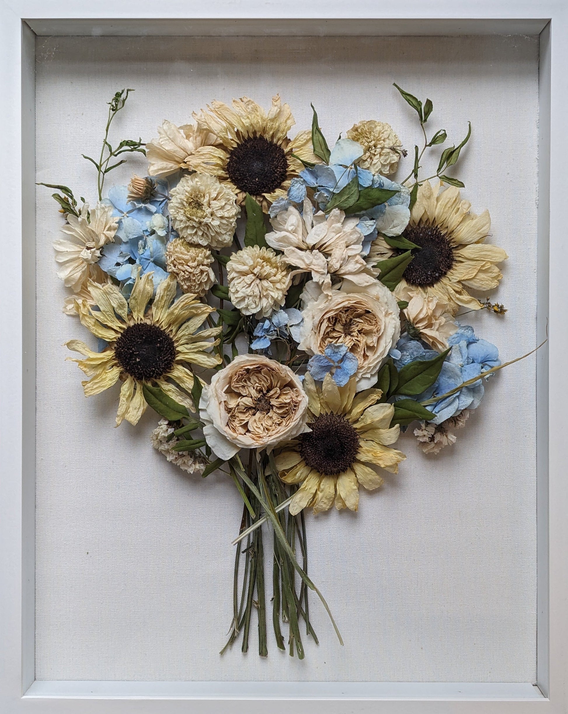 Framed arrangement of pressed flowers on a wooden surface