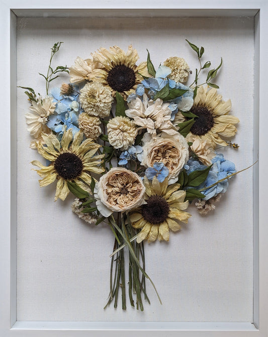 Framed arrangement of pressed flowers on a wooden surface