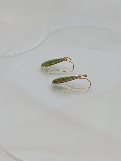 Gold earrings with green leaves on a white background