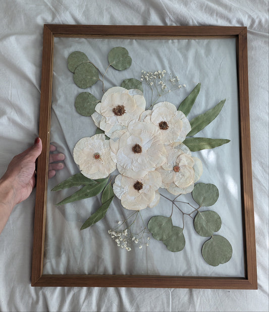 Framed artwork with white flowers and green leaves on a white background
