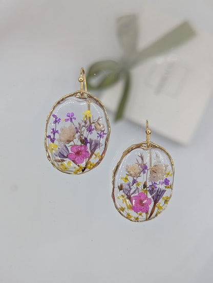 Oval-shaped earrings with floral design on a light gray background