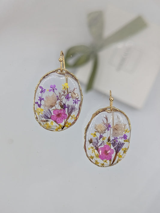 Oval-shaped earrings with floral design on a light gray background