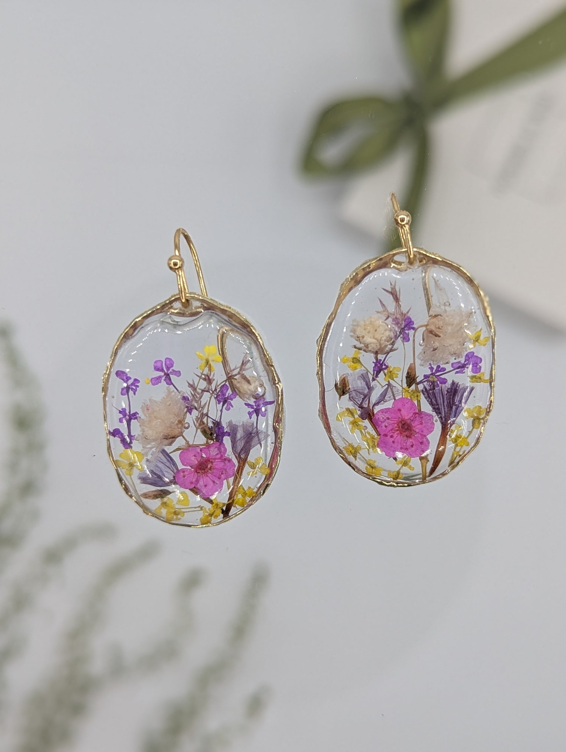 Oval-shaped earrings with floral design on a light background