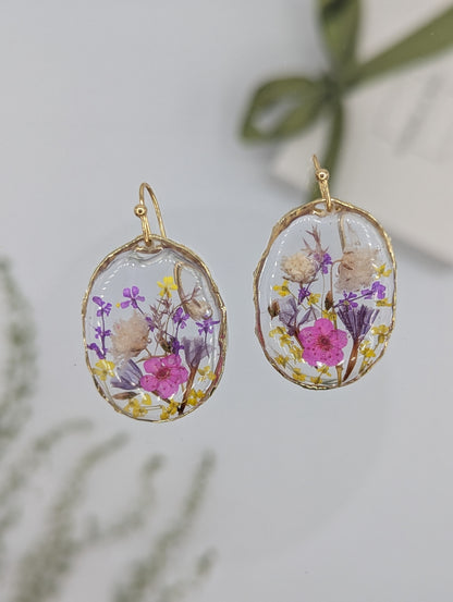 Oval-shaped earrings with floral design on a light background