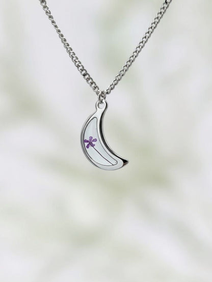 Silver necklace with a crescent moon pendant on a blurred background