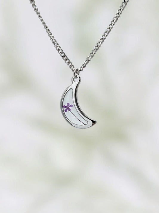 Silver necklace with a crescent moon pendant on a blurred background