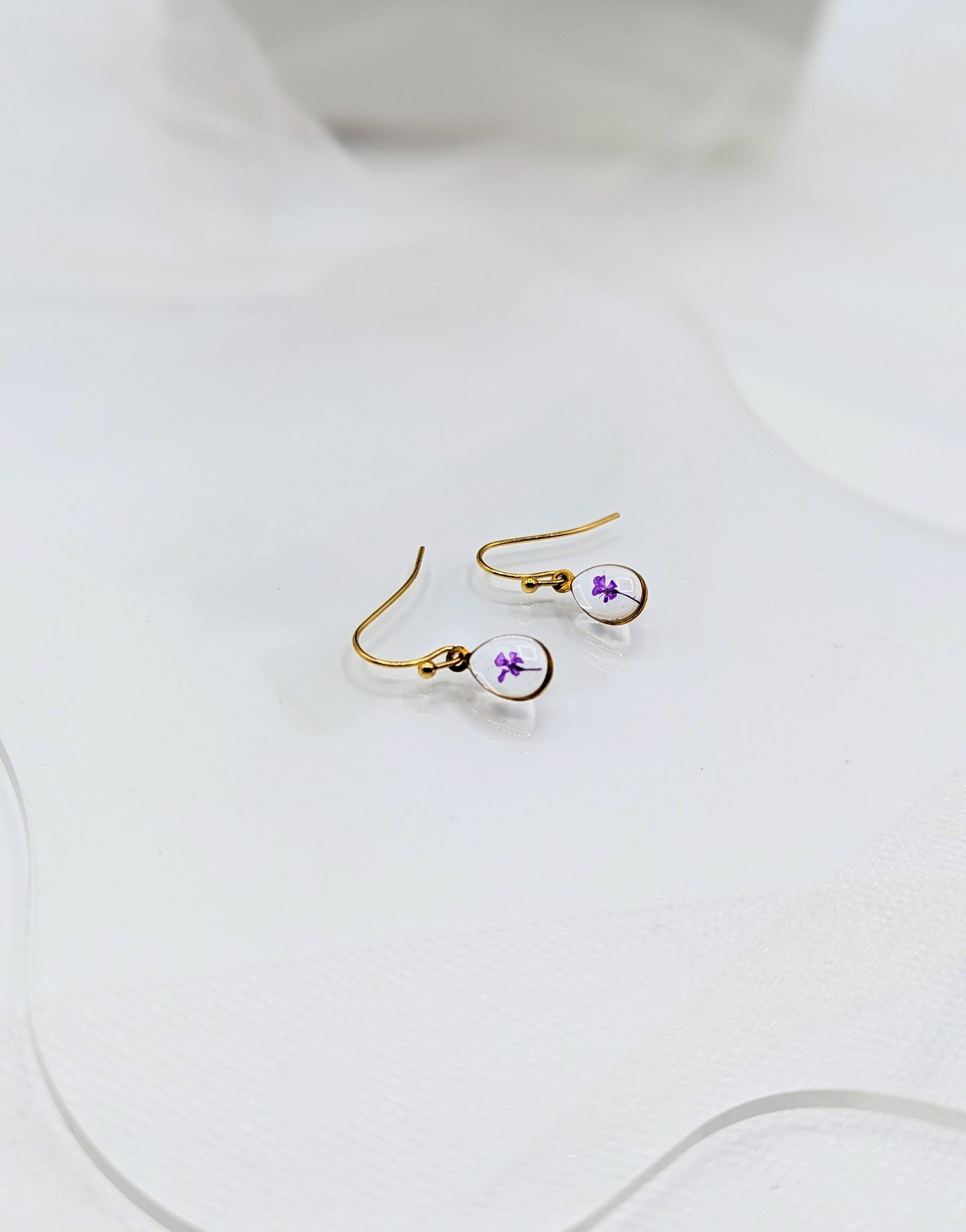 Gold earrings with purple accents on a white surface