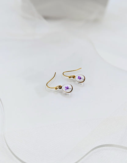Gold earrings with purple accents on a white surface