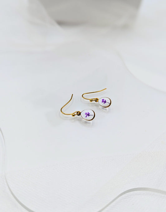 Gold earrings with purple accents on a white surface