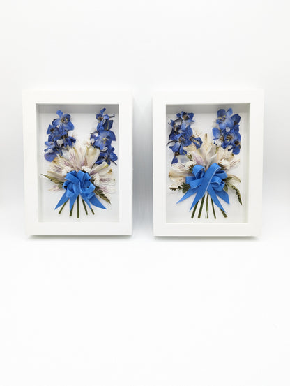 Two framed bouquets of flowers with blue ribbons on a white background