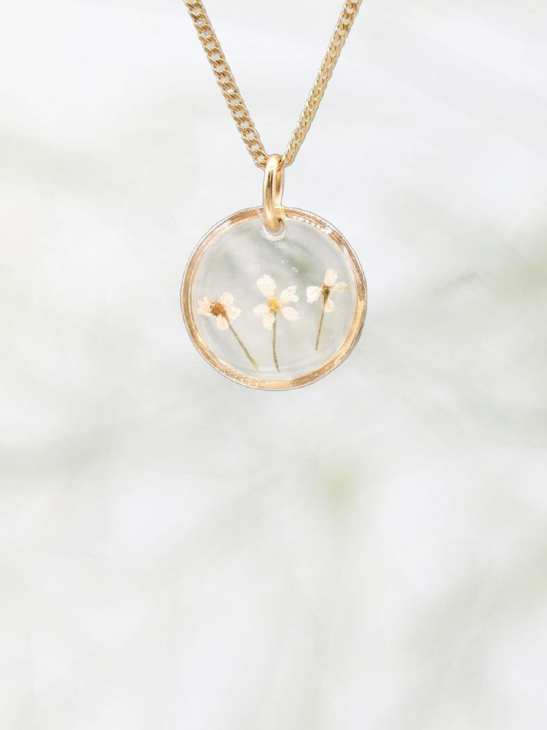 Gold necklace with a round pendant on a white background