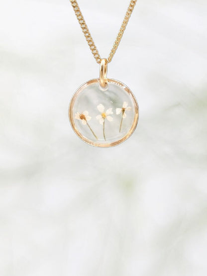 Gold necklace with a round pendant on a white background