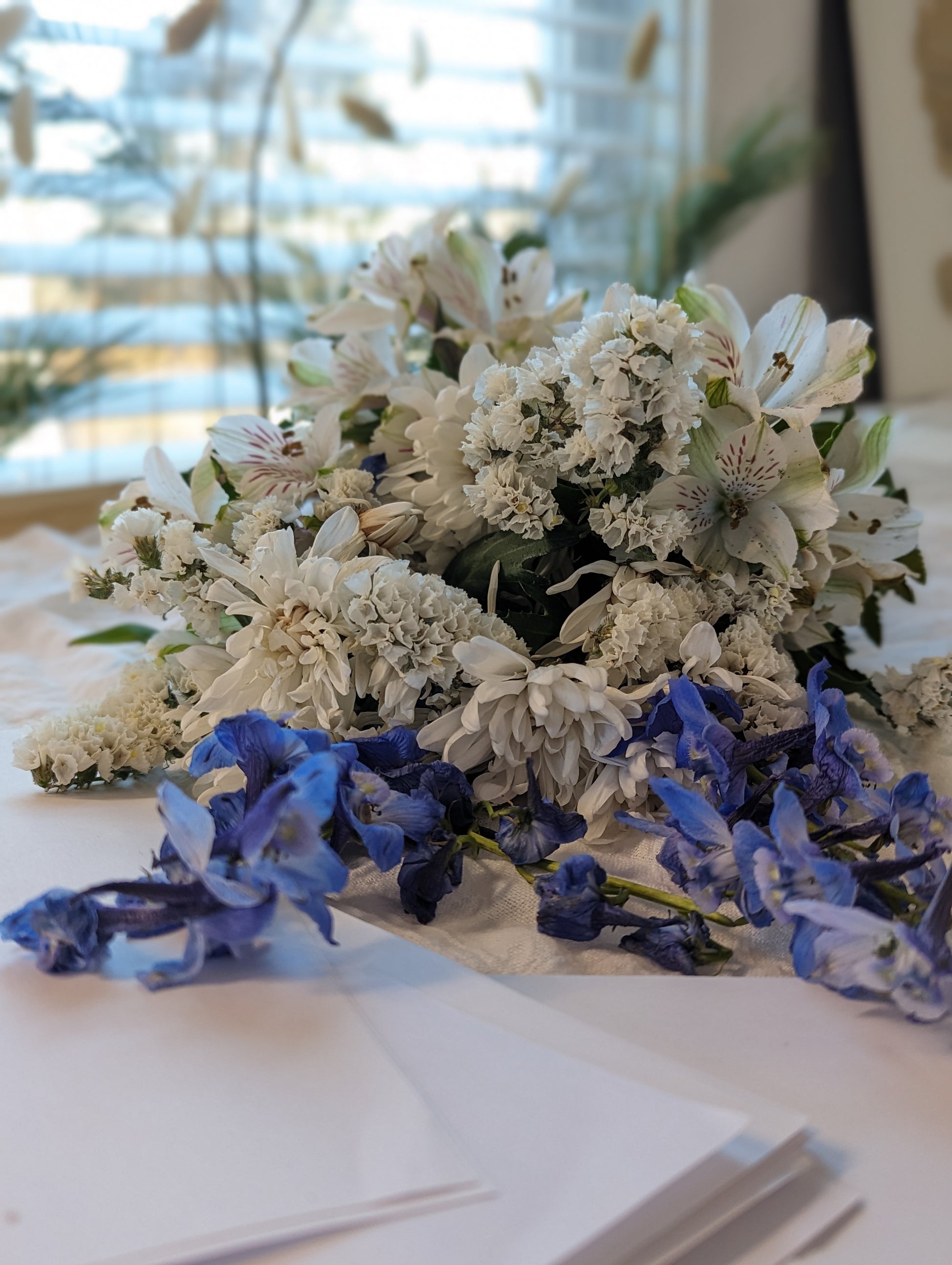 Bouquet of white and blue flowers on a table with a blurred indoor background