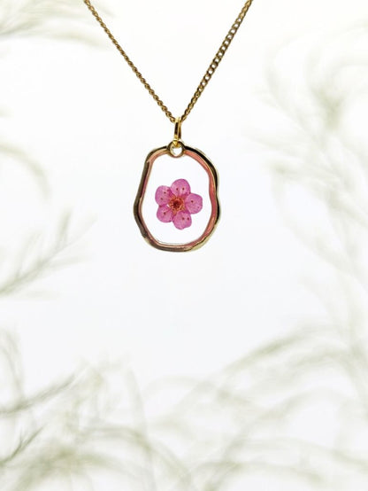 Necklace with a pink flower pendant on a white marble background