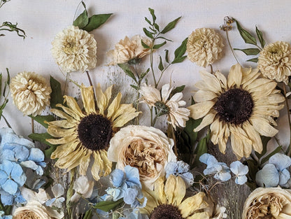Decorative arrangement of pressed flowers in a white frame on a wooden surface