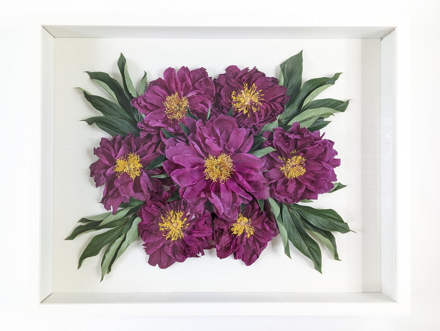 Framed artwork of purple flowers with green leaves on a white background