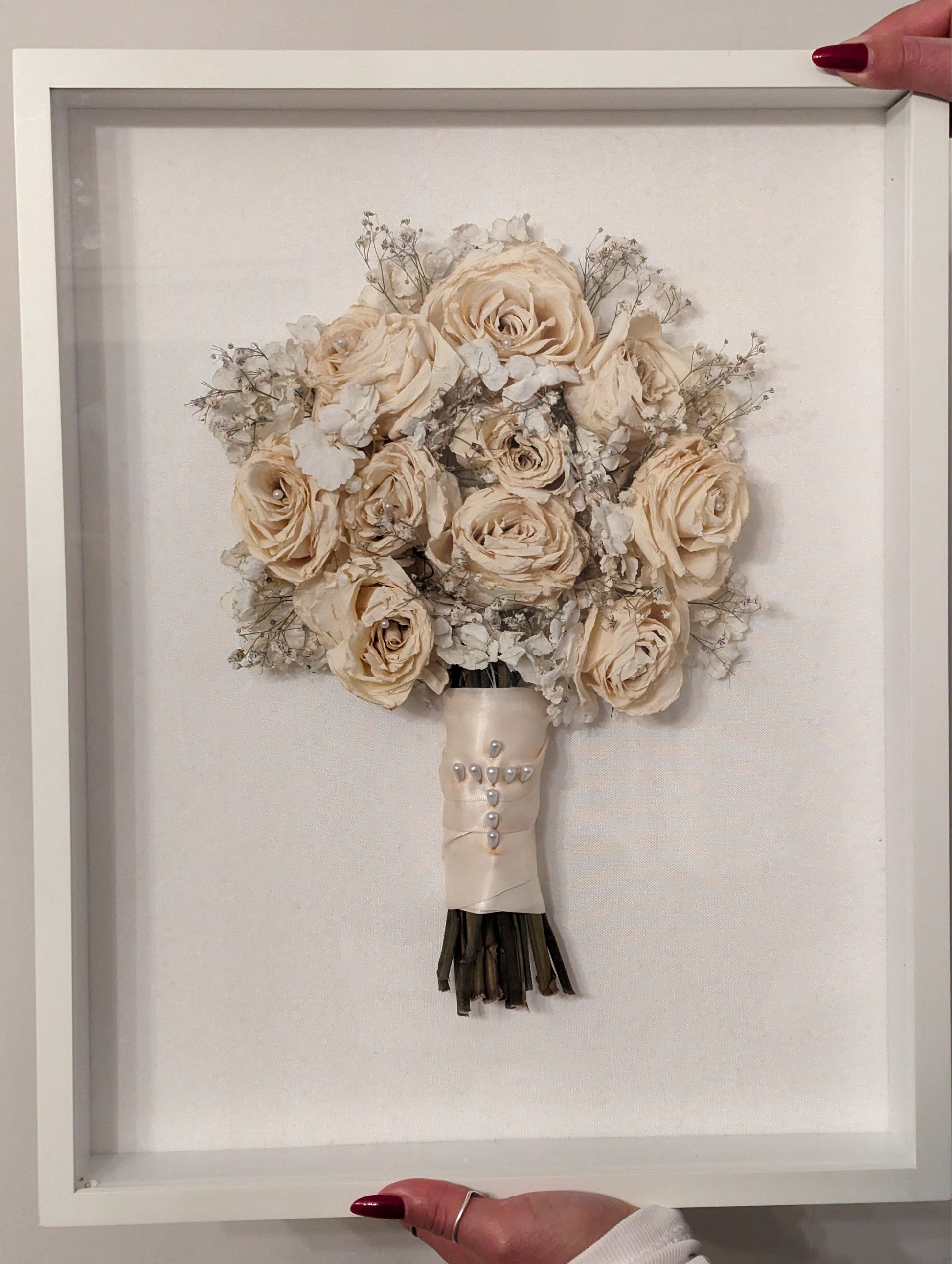 Framed bouquet of beige flowers held by a person