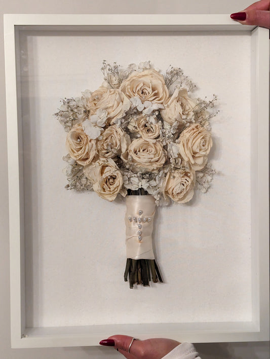 Framed bouquet of beige flowers held by a person